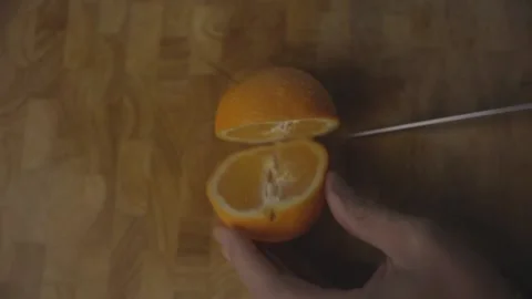 Orange Being Cut in Half From Above Top Down on Wooden Cutting Board LOG Stock Footage 136992429