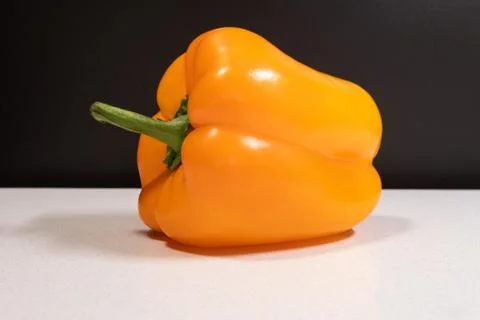 Orange bell pepper. Vegetable. Dark background and white chopping board. Stock Photos