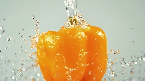 Orange bell pepper washed with stream of clear water in slow motion Stock Footage 327573318