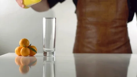 The orange beverage is quickly pouring into the high glass with the help of man Vidéo 75414415