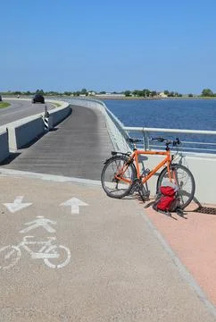 Orange bicycle and red backpack parked along scenic coastal cycle path on s.. 库存照片
