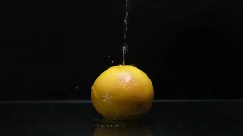 Orange on a black background on which a stream of water pours Stock-Footage 168529218