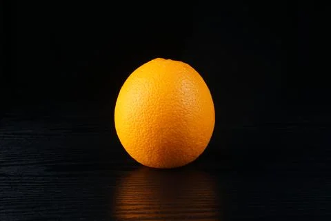 An orange on a black table Stock Photos