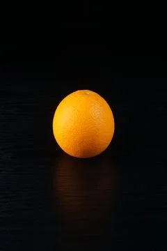 An orange on a black table Stock Photos