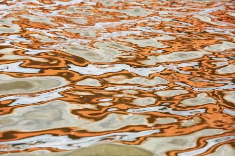 Orange blue white reflection on surface water with waves Foto stock