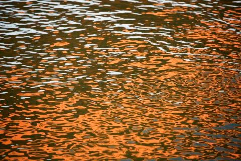Orange blue white reflection on surface water with waves Stock Photos