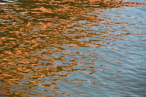 Orange blue white reflection on surface water with waves Stock Photos