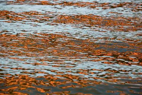 Orange blue white reflection on surface water with waves Stock Photos