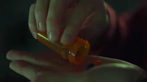 An orange bottle of pills in the hands of a young man. Close-up of male hand Stock Footage 256939319
