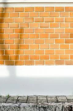 Orange brick wall with white cement painted wall and pavement and tree shadow Stock Photos