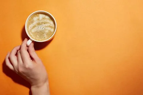 Orange bright background with a cup of coffee in hand. The concept of a positive Stock Photos