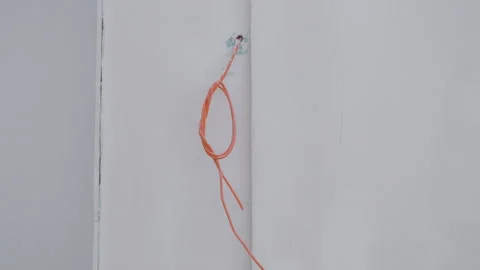 Orange cable looped around a wall anchor, gradually shifting position across Stock Footage 319530464