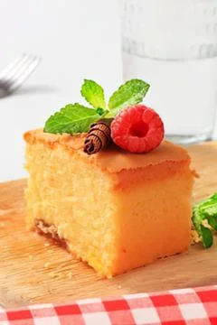 Orange cake slice with raspberry and mint garnish Stock Photos