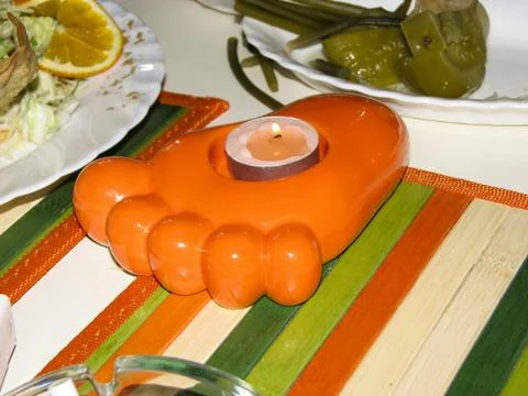 Orange candle in the shape of a frog on a table with vegetables Stock Photos