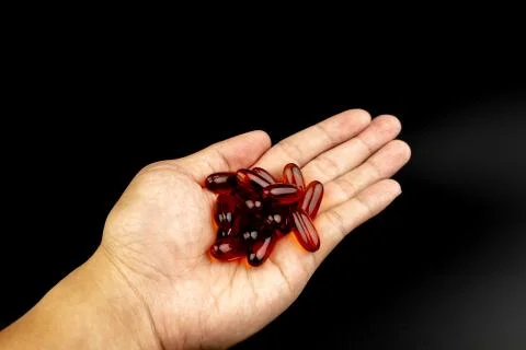 Orange capsules on hand Stock Photos
