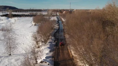 An orange car drives quickly through puddles through the forest, view from a qua Stock Footage 280460238