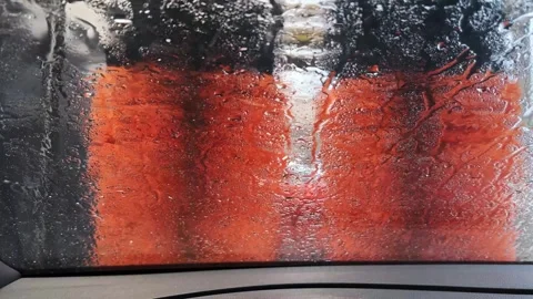 Orange Car Wash Brushes Spin Against a Wet Windshield View Stock Footage 334572867