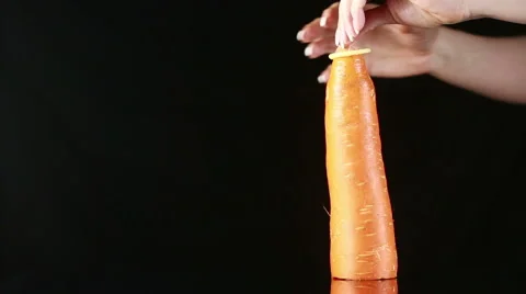 Orange carrot with a condom on a black background Stock Footage 62478847