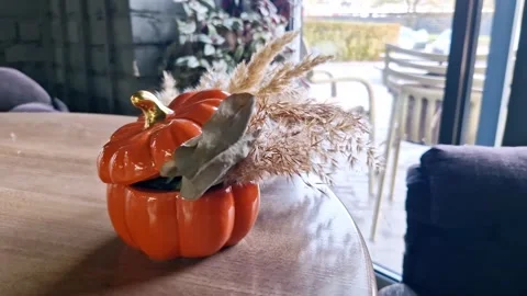 Orange Ceramic Pumpkin with Dried Pampas Grass on Table Near Window Stock Footage 322534926