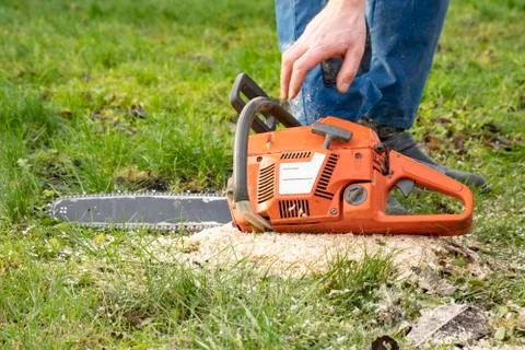 Orange chainsaw lying on the grass Stock Photos