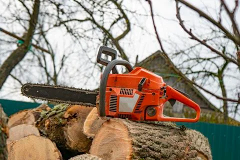 Orange chainsaw lying on a log Stock Photos