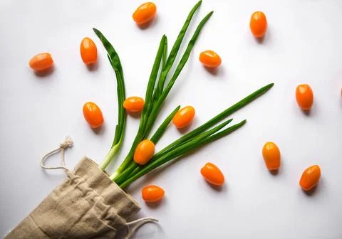 Orange cherry tomatoes flat lay with parsley greens in a cloth bag on a whi.. Stock Photos