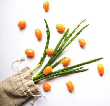 Orange cherry tomatoes flat lay with parsley greens in a cloth bag on a whi.. Stock Photos