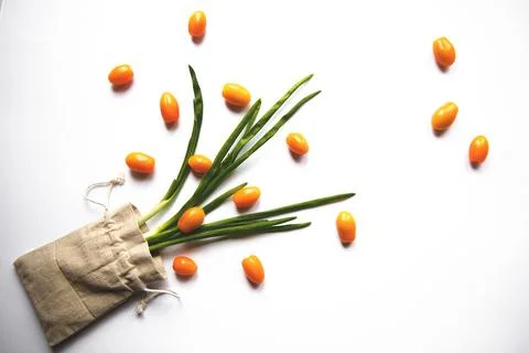 Orange cherry tomatoes flat lay with parsley greens in a cloth bag on a whi.. Stock Photos