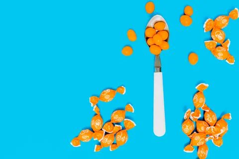 Orange chocolates inside a white spoon on a blue background and assortment of Stock Photos