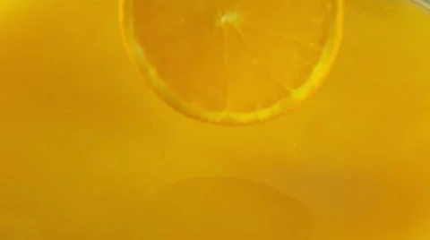 Orange circle falling into the orange juice Stock Footage 48420373