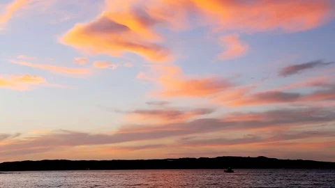 Orange Clouds Against Blue Sky with Small Boat in the Ocean 1 Stock Footage 90242990