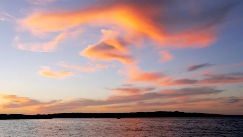 Orange Clouds Against Blue Sky with Small Boat in the Ocean 2 Stock Footage 90403305