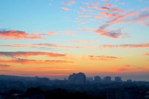 Orange clouds on a blue sky at dawn just before sunrise over the sleeping city Stock Photos