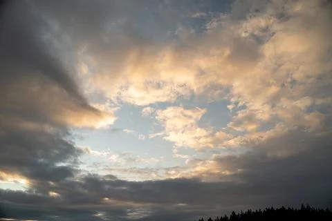 Orange clouds at sunset with overcast sky Stock Photos