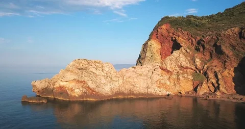 Orange colored cliffs by the sea on a sunny day Stock Footage 108724813