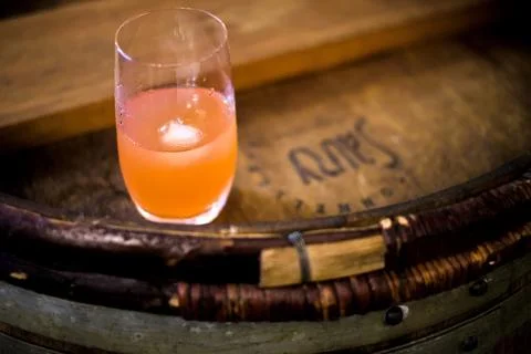 Orange colored drink resting on rustic wooden barrel Stock Photos