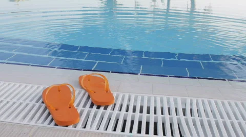 Orange Colored Flip Flop Sandals By The Side Of A Swimming Pool Stock Footage 630596