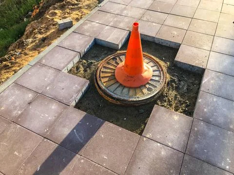 Orange cone triangular shape mounted on asphalt. the cone rests on a hole wit 스톡 사진