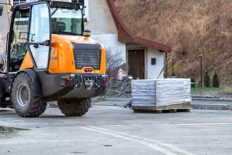 An orange construction loader sits at a residential work site with a pallet of Stock Photos