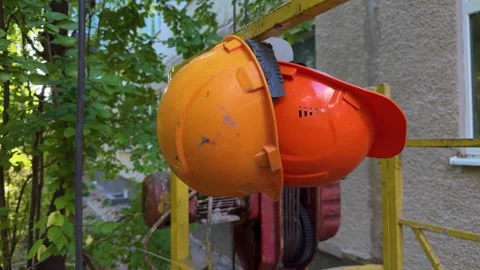 Orange construction safety helmets hanging on a metal railing outdoors Video stock 346516272