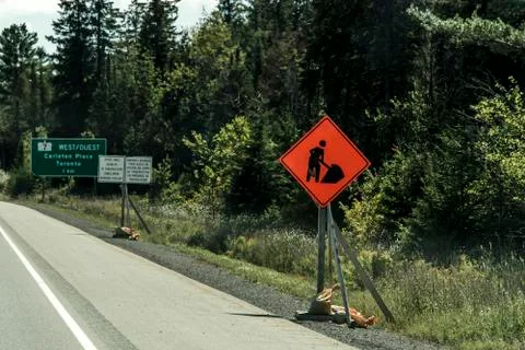 Orange construction worker sign at road into the distance on trans canada Stock Photos