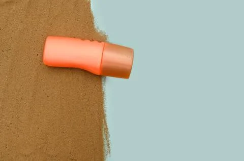 Orange container with protective sunscreen. On the sand. Seaside concept. Stock Photos