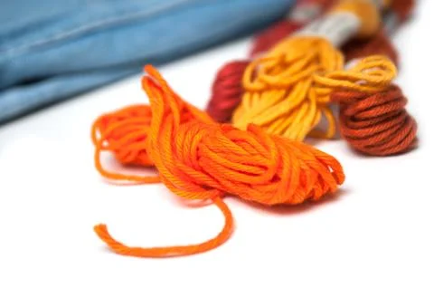 Orange  cotton threads on white table on blue jeans background Stock Photos
