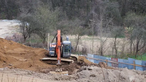Orange crawler excavator digging earth at construction site. Stockbeeldmateriaal 332133968