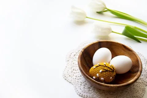 Orange crocheted Easter egg and white raw chicken eggs in a wooden plate on a Stock Photos
