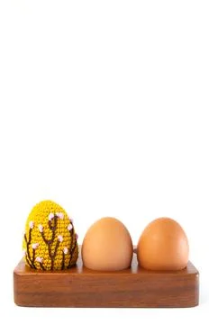 Orange crocheted Easter egg and eggs on a wooden stand on a white background. Stock Photos