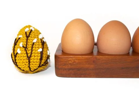 Orange crocheted Easter egg and eggs on a wooden stand on a white background. Stock Photos
