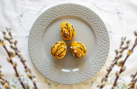 Orange crocheted Easter eggs on a plate on a white tablecloth. Easter handmad Stock Photos