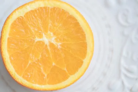 Orange cut in half pulp to the top on white patterned plate. Top view. Copysp Stock-Fotos