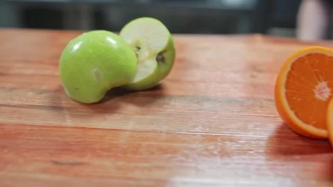 An orange cut into halves, an sliced apple and an onion lay on the table. Stock Footage 264281338